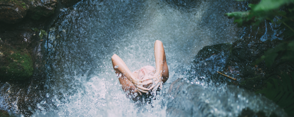 Woman beneath a waterfall