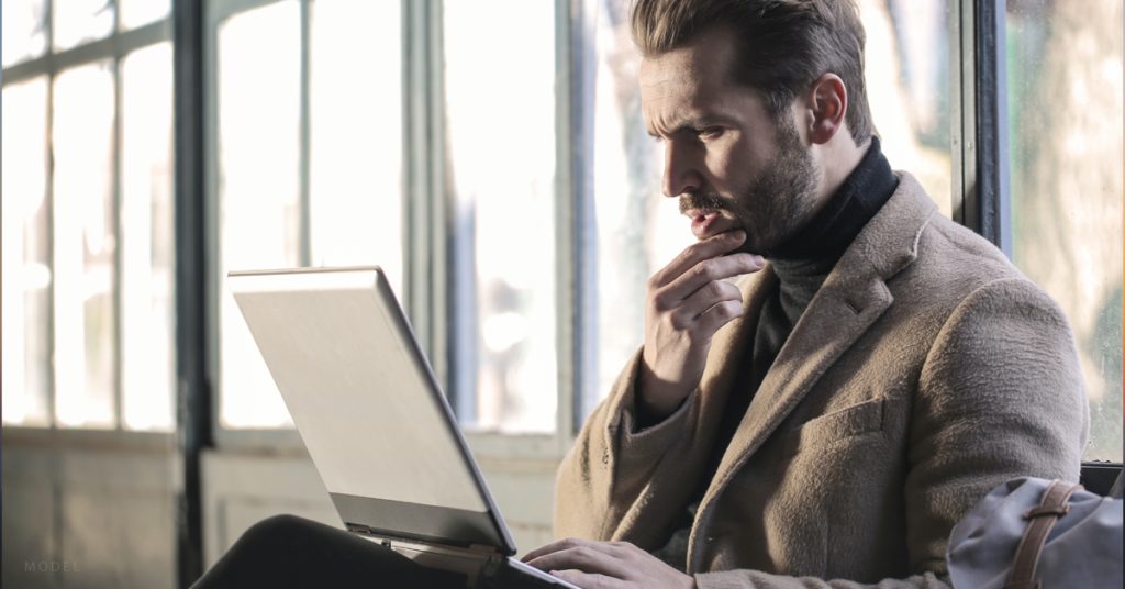 A man considering hormone replacement therapy researches costs for treatment on a laptop.