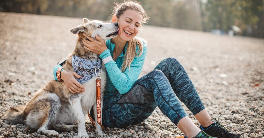 A woman who uses treatments offered by Rejuvime Medical pets her dog after a strenuous a hike.