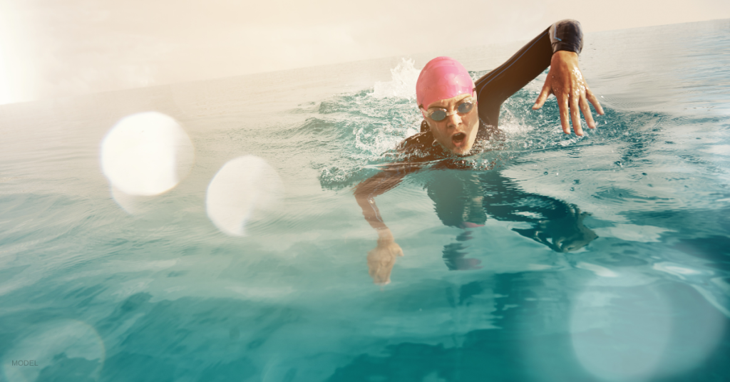 A woman swims head-up freestyle in open water.