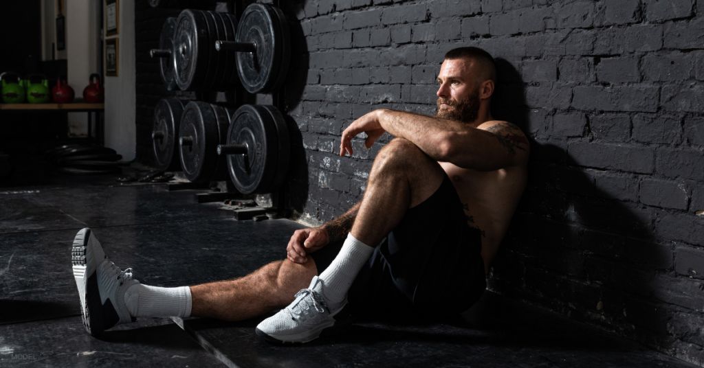 A fatigued man pauses for a break during his workout.