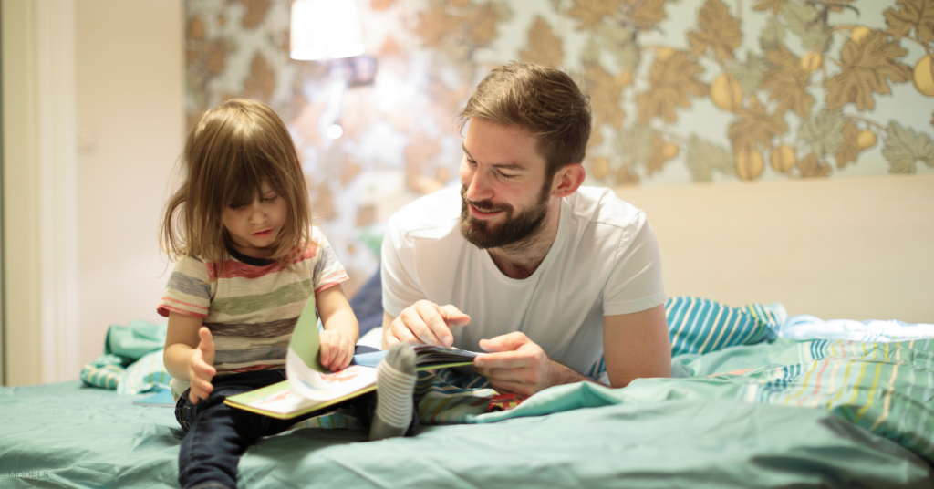 A dad and his daughter stay up after bedtime reading.