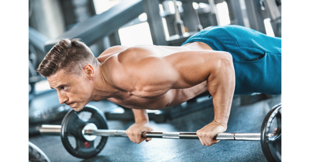 A man doing a workout in the gym with a bar and weights.