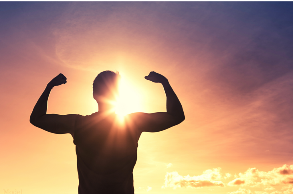 Man flexing in the sunrise feeling rejuvenated and healthy