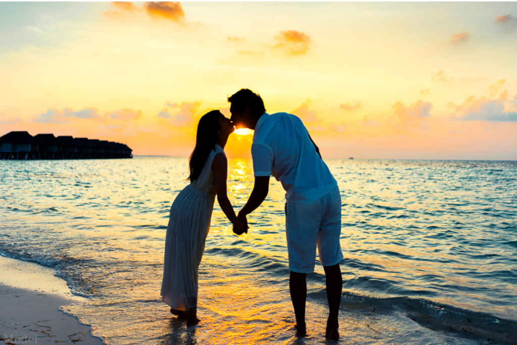 Man and woman enjoying time together on a beach kissing