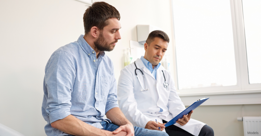 Male doctor and male patient reviewing doctors notes on a clipboard (models)