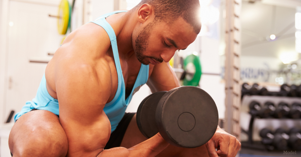 Middle aged man lifting a dumbbell in the gym (model)