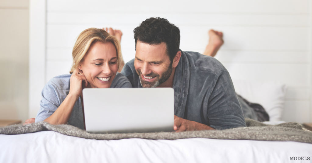 Man and woman woman smiling while researching on the computer (models)