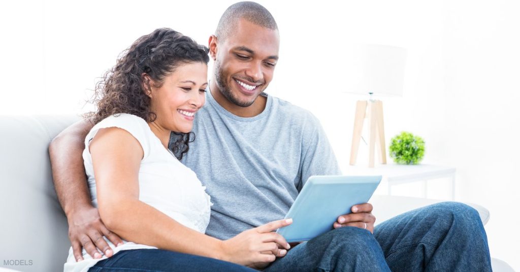 An adult couple looking at a computer together (models)