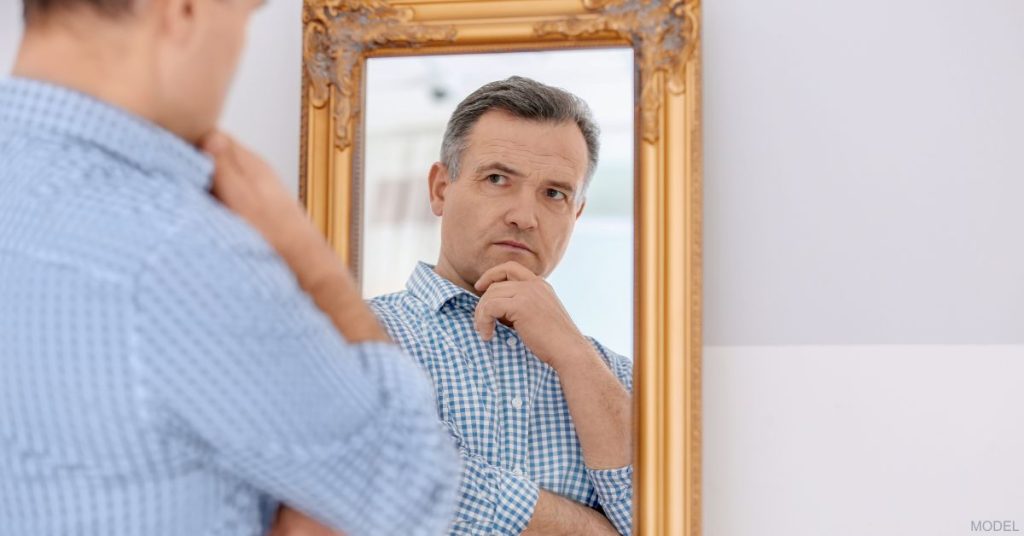 A man pondering and looking at himself in the mirror (model)