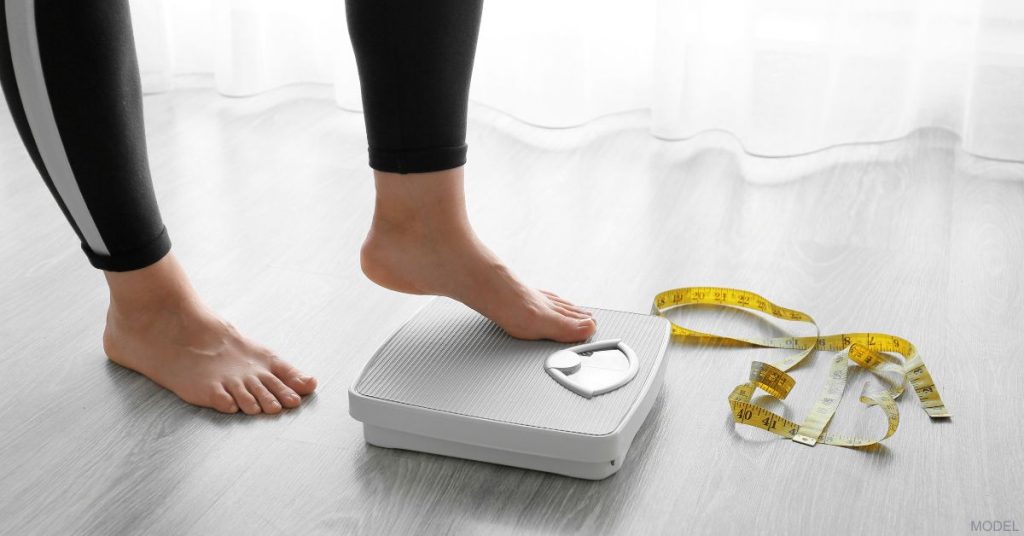 A woman stepping onto the scale (model)