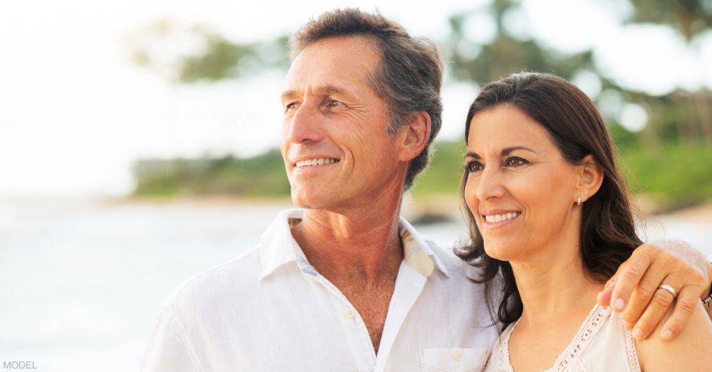 A mature couple looking at the view on the beach (model)